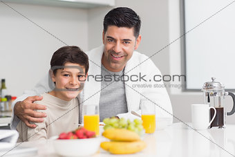 Young son with father having breakfast in kitchen
