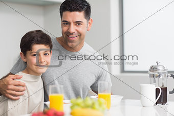 Portrait of happy son with father having breakfast