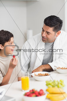 Smiling young son with father having breakfast