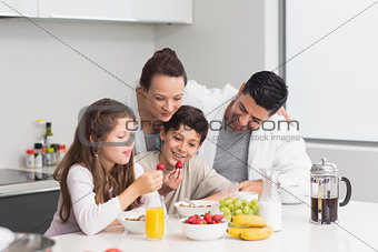 Happy kids enjoying breakfast with parents in kitchen