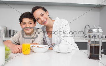 Portrait of a smiling mother with son in kitchen