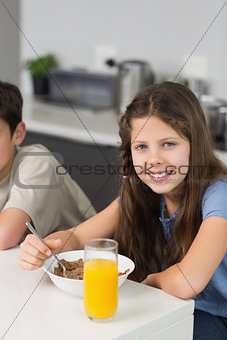 Portrait of two smiling siblings enjoying breakfast