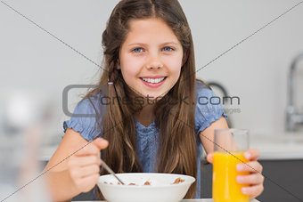 Smiling young girl enjoying breakfast in kitchen