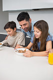 Young kids enjoying breakfast with father in kitchen