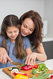 Woman with daughter chopping vegetables in kitchen