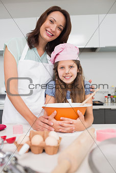 Portrait of girl and mother preparing cookies in kitchen