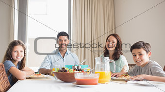 Portrait of happy family of four sitting at dining table