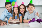 Family of four with cake and gifts at birthday party