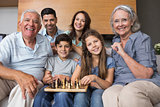 Portrait of happy extended family playing chess in living room