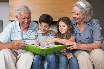 Happy grandparents and grandkids looking at album photo