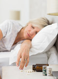Woman sleeping in bed with pills in foreground
