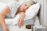 Woman sleeping in bed with pills in foreground