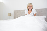 Pretty smiling woman sitting on bed