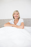 Pretty smiling mature woman sitting on bed