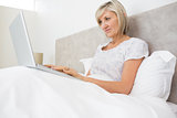 Woman using laptop in bed at home