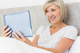 Smiling woman using digital tablet in bed