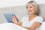 Mature woman using digital tablet in bed
