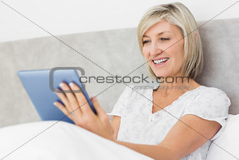 Mature woman using digital tablet in bed
