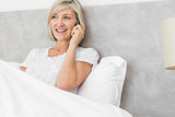 Mature woman using mobile phone in bed