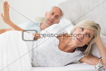Woman ignoring mature man while lying in bed