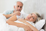 Woman ignoring mature man in bed
