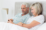 Concentrated couple using digital tablet in bed