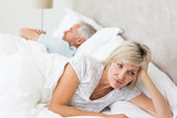 Tensed woman lying besides man in bed