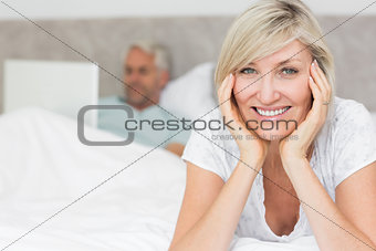 Happy mature woman with man using laptop in bed