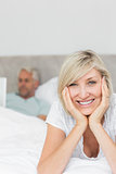 Happy woman with man using laptop in bed