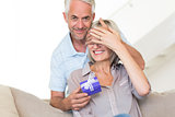 Smiling mature man surprising woman with a gift