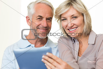 Closeup of a smiling mature couple using digital tablet