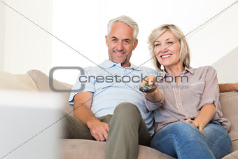 Happy couple watching tv on sofa