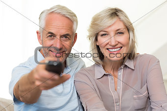 Happy mature couple watching tv at home