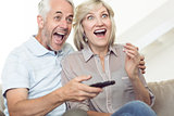 Cheerful couple watching tv on sofa