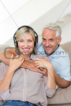 Mature man embracing woman from behind on sofa