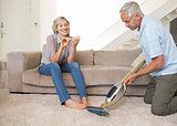Woman filing nails while man vacuuming area rug