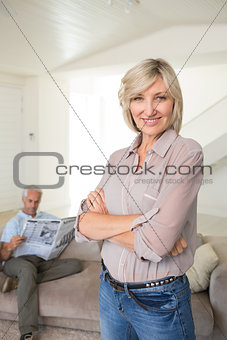 Smiling woman with man reading newspaper at home