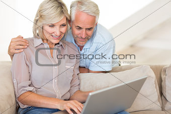 Mature couple using laptop on sofa