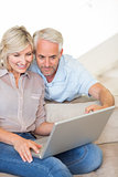 Mature couple using laptop on sofa at home