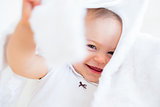 Closeup of a cheerful cute baby under comforter