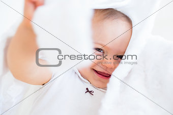 Closeup of a cheerful cute baby under comforter
