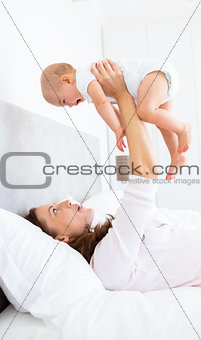 Mother playing with baby in the bed