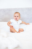 Full length portrait of cute baby sitting on bed
