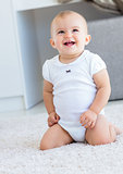 Cute cheerful baby sitting on carpet
