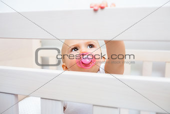 Cute baby with pacifier in mouth in the crib