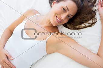 Portrait of a smiling young woman lying in bed