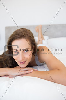 Pretty smiling young woman lying in bed