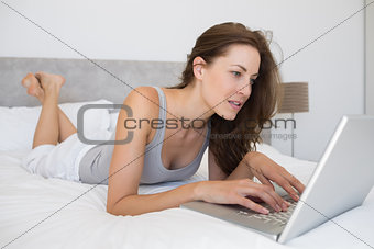 Relaxed woman using laptop in bed