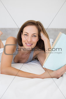 Pretty relaxed woman reading book in bed