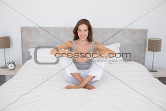Pretty smiling young woman sitting on bed